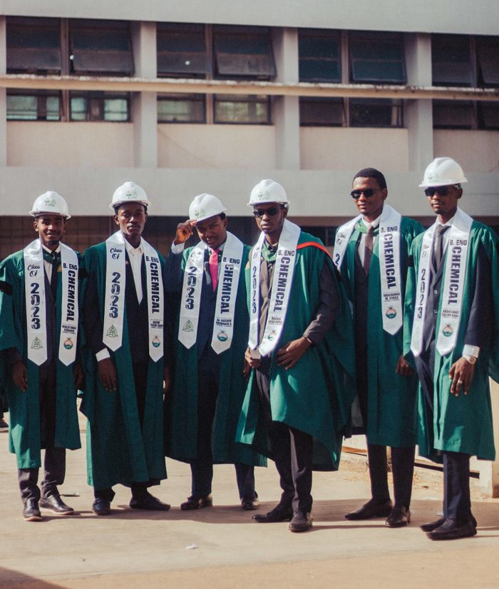 Confident young engineer wearing a hard hat and graduation stole celebrating academic achievement.